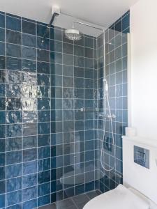a blue tiled bathroom with a shower and a toilet at Sjælegård Countryside Lodge in Allinge