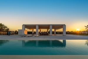a pavilion with a pool in front of a sunset at Villa Brigida Resort in Santeramo in Colle