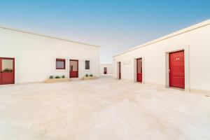 Habitación grande con paredes blancas y puertas rojas. en Villa Brigida Resort, en Santeramo in Colle