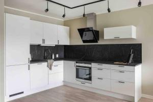 a kitchen with white cabinets and a black counter top at Nyleilighet midt i sentrum in Leknes