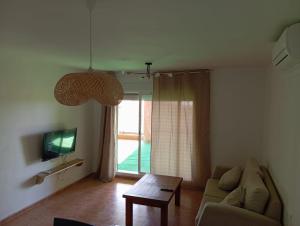 a living room with a couch and a table and a tv at Center Paradise Almerimar in Almerimar