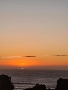 um pôr-do-sol sobre o oceano com uma linha eléctrica em Azul petroleo em Concón