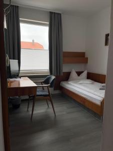 Schlafzimmer mit einem Bett, einem Schreibtisch und einem Fenster in der Unterkunft Hotel Passat in Borkum