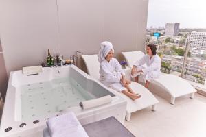 two women sitting in a bathroom with a bath tub at Valia Bangkok Sukhumvit 24 by Kingston Hotels in Bangkok