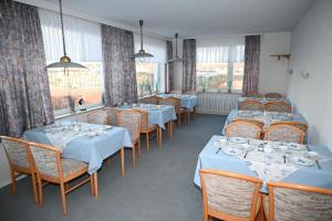 a dining room with tables and chairs and windows at Hotel Passat in Borkum