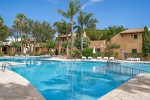 a swimming pool with blue water and palm trees at Menorca Paradise nº 30 in Son Xoriguer