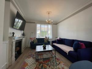 a living room with a blue couch and a table at Windsor Stunning Three Bedroom House in Windsor