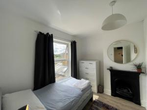 a bedroom with a bed and a mirror and a window at Windsor Stunning Three Bedroom House in Windsor