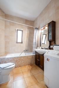 ein Badezimmer mit einer Badewanne, einem WC und einem Waschbecken in der Unterkunft Apartment Villa Omega in Agia Pelagia