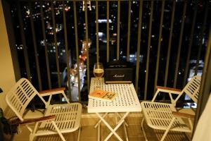 d'une table et de chaises avec un verre de vin sur le balcon. dans l'établissement Lisa Apartment - SOHO Residence, à Hô-Chi-Minh-Ville