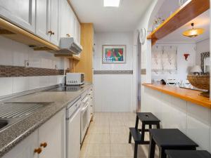 a kitchen with white cabinets and black stools at Apartment Novamar by Interhome in Puerto Marino