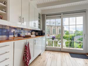 a kitchen with white cabinets and a large window at Holiday Home Dijkhuisje by Interhome in Brouwershaven