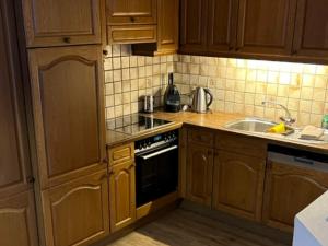 uma cozinha com armários de madeira, um fogão e um lavatório em Apartment Chalet Murmeli by Interhome em Engelberg