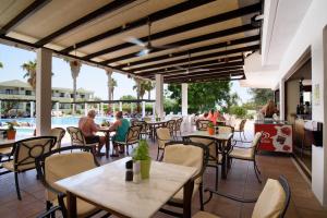 a restaurant with tables and chairs and a pool at Pefkos Village Resort in Pefki Rhodes