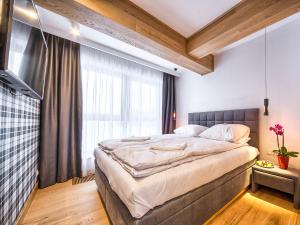 een slaapkamer met een groot bed en een groot raam bij VisitZakopane - Chalet Ski Apartment in Zakopane
