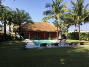 a house with a swimming pool and palm trees at Villa avec piscine près de l'océan. in Cap Skirring