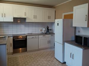 a kitchen with white appliances and white cabinets at Holiday Home Ruiterlaan with parking by Interhome in Bredene