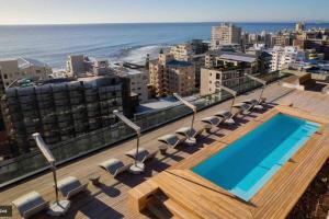 a swimming pool on top of a building with the ocean at Station House Ocean View Apartment in Cape Town