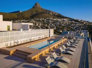 a building with a swimming pool and a mountain at Station House Ocean View Apartment in Cape Town