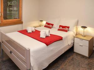 a large white bed with red pillows on it at Apartment Turquino C by Interhome in Zermatt