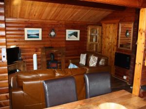 a living room with a leather couch in a cabin at Chalet Highand Lodges-1 by Interhome in Spean Bridge