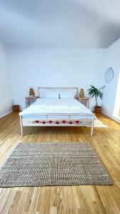 un letto bianco in una stanza con un tappeto di BioLocalia House Dobrogea a Baloteşti