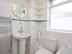 a white bathroom with a sink and a toilet at Sandy Haven in Swanage +29 photos