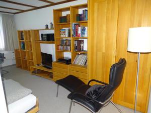 uma sala de estar com uma cadeira e uma estante de livros em Apartment Parkweg 9-602 by Interhome em Engelberg