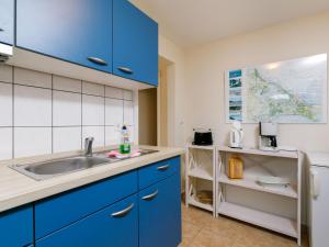 eine Küche mit blauen Schränken und einer Spüle in der Unterkunft Holiday Home Fischerbungalow by Interhome in Zempin