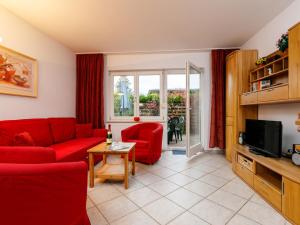 a living room with a red couch and a tv at Holiday Home Susi by Interhome in Ostseebad Koserow +19 photos