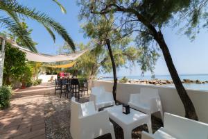 a restaurant with white chairs and a beach at Testa di Monaco Natural Beach in Capo dʼOrlando