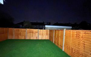 ミッチャムにあるLondon Mitcham Beautifully Presented Two Bedroom Apartmentの夜の裏庭の緑の芝生の柵