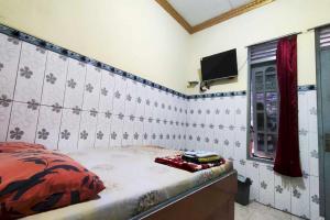 - une chambre avec un lit et une télévision murale dans l'établissement OYO 93396 Pondok Wisata Sri Mulyo, à Yogyakarta