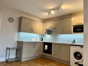 uma cozinha com armários brancos e uma máquina de lavar roupa em Pass the Keys Charming Guest House in St Albans with Parking em Saint Albans