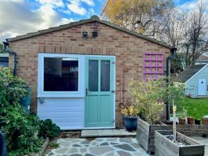 a garage with a blue door and a brick house at Pass the Keys Charming Guest House in St Albans with Parking in St. Albans