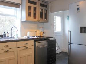 a kitchen with a sink and a refrigerator at Le Grand Bleu, 1 Court Cottages in Kingsbridge
