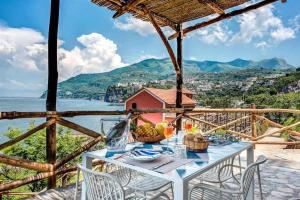 a white table with chairs and a view of the water at GOCCE VILLAS - Villa Degli Dei Maestrale in Vico Equense