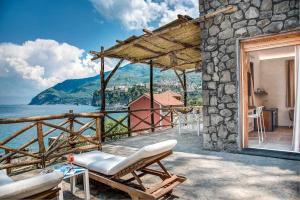 a patio with chairs and a view of the water at GOCCE VILLAS - Villa Degli Dei Maestrale in Vico Equense