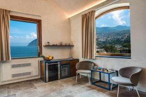 a living room with two chairs and a large window at GOCCE VILLAS - Villa Degli Dei Maestrale in Vico Equense +2 photos