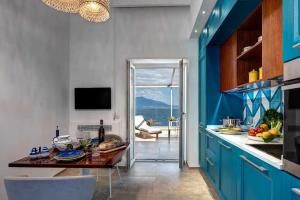 a kitchen with blue cabinets and a dining table at Villa Tramontana Stunning Waterfront Villa in Vico Equense