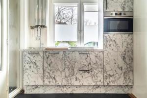 a kitchen with white marble counters and a window at BEAUTIFUL APARTMENT WiTH ASIAN STYLE BEDROOM NEAR RAI & CENTER in Amsterdam