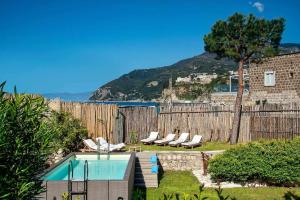 a backyard with a swimming pool and chairs and a fence at GOCCE VILLAS - Villa Degli Dei Scirocco in Vico Equense