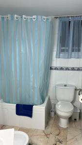 a bathroom with a toilet and a blue shower curtain at Apartamento Córdoba FAMORCAS in Almodóvar del Río