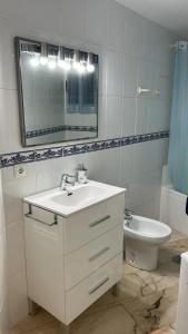 a bathroom with a sink and a mirror and a toilet at Apartamento Córdoba FAMORCAS in Almodóvar del Río