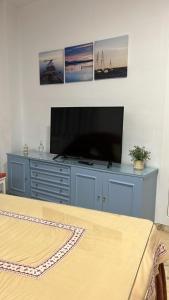a flat screen tv sitting on top of a blue dresser at Apartamento Córdoba FAMORCAS in Almodóvar del Río