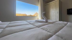 Una cama blanca con un cisne en un dormitorio en Pyramids Land Hotel en El Cairo