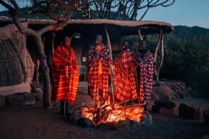 Un groupe d'hommes debout autour d'un feu dans l'établissement Maji Moto Eco Camp, à Maji Moto