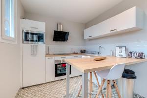 a kitchen with white cabinets and a wooden table at The Bac is back à 2 pas de la Gare in Limoges