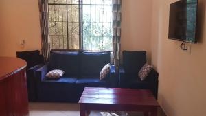 a living room with a blue couch and a window at Camp Seluu - Safari Pkg in Kwangwazi