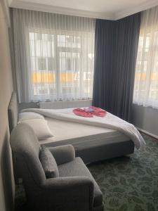 a bed in a room with a chair and windows at Samsun Otel Vidinli in Samsun